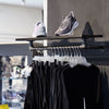 Wall mounted display rack in clothes store with strong iron rail made from water pipes and wooden shelf on top